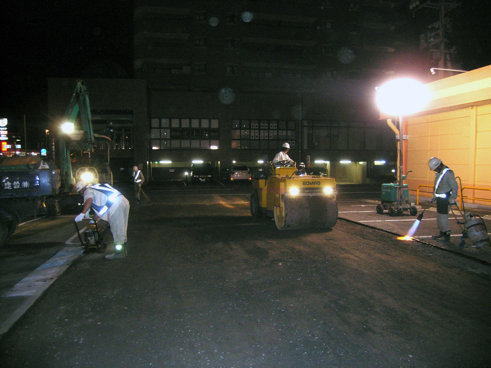 整地された地面をロードローラーで締め固めている夜間の作業風景
